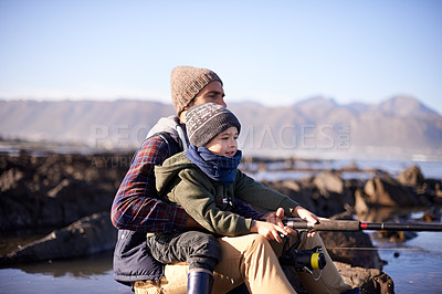 Buy stock photo Father, fishing and young boy on rocks, teaching and bonding for activity by ocean. Sea, rod and learning how to fish for childhood development, winter and hobby together while on seaside vacation