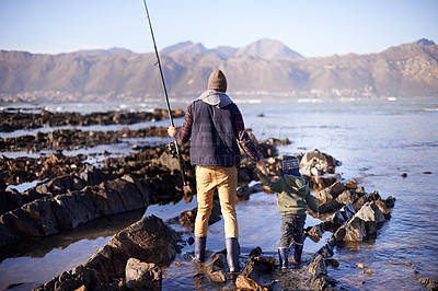 Buy stock photo Man, kid and beach for fishing in winter as hobby with bonding for child development, growth and life skills in Australia. Dad, boy and stand in rocks at coast for family tradition, memory and care