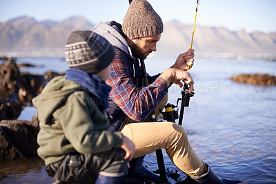Buy stock photo Shot of a cute little boy fishing with his father by the sea