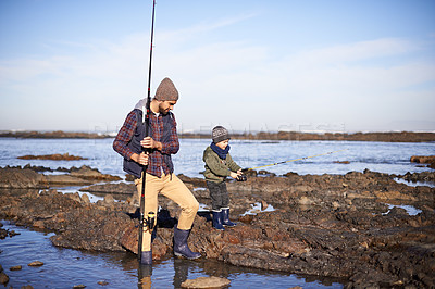 Buy stock photo Shot of a father and son out fishing together by the sea