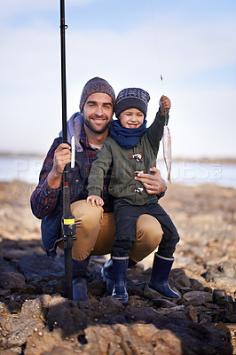 Buy stock photo Portrait, son and smile with father, fish and happiness for achievement on break. Family, water and ocean with rocks, adventure and vacation on bonding fishing trip for childhood memories and success