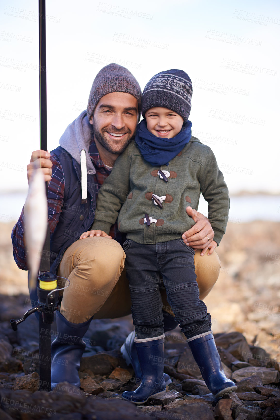 Buy stock photo Portrait, kid and smile with dad, fish and happiness for achievement on break. Child, water and ocean with rocks, adventure and vacation on fishing trip with childhood memories and fun success