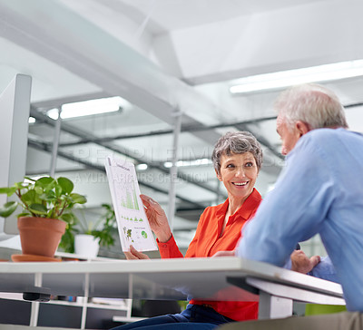 Buy stock photo Shot of two mature business colleagues discussing a document at a desk