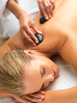 Buy stock photo Woman, hot stone massage and spa with hands of masseuse, peace and treatment for destress at luxury resort. Serene, zen and calm with stress relief, self care and wellness with warm rocks for detox