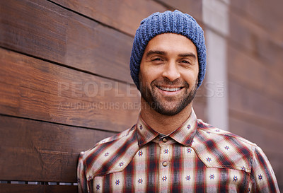 Buy stock photo Portrait, smile and man on wood wall background outdoor in casual clothes, outfit or apparel. Face, happy and stylish person in beanie, shirt and trendy fashion for profile picture with hat in Spain
