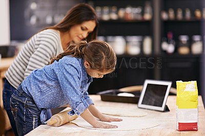 Buy stock photo Shot of a mother and daughter baking in the kitchen with a digital tablet beside them