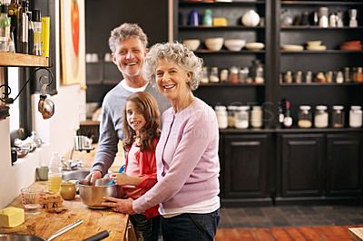 Buy stock photo Portrait of a little girl and her grandparents baking together in the kitchen