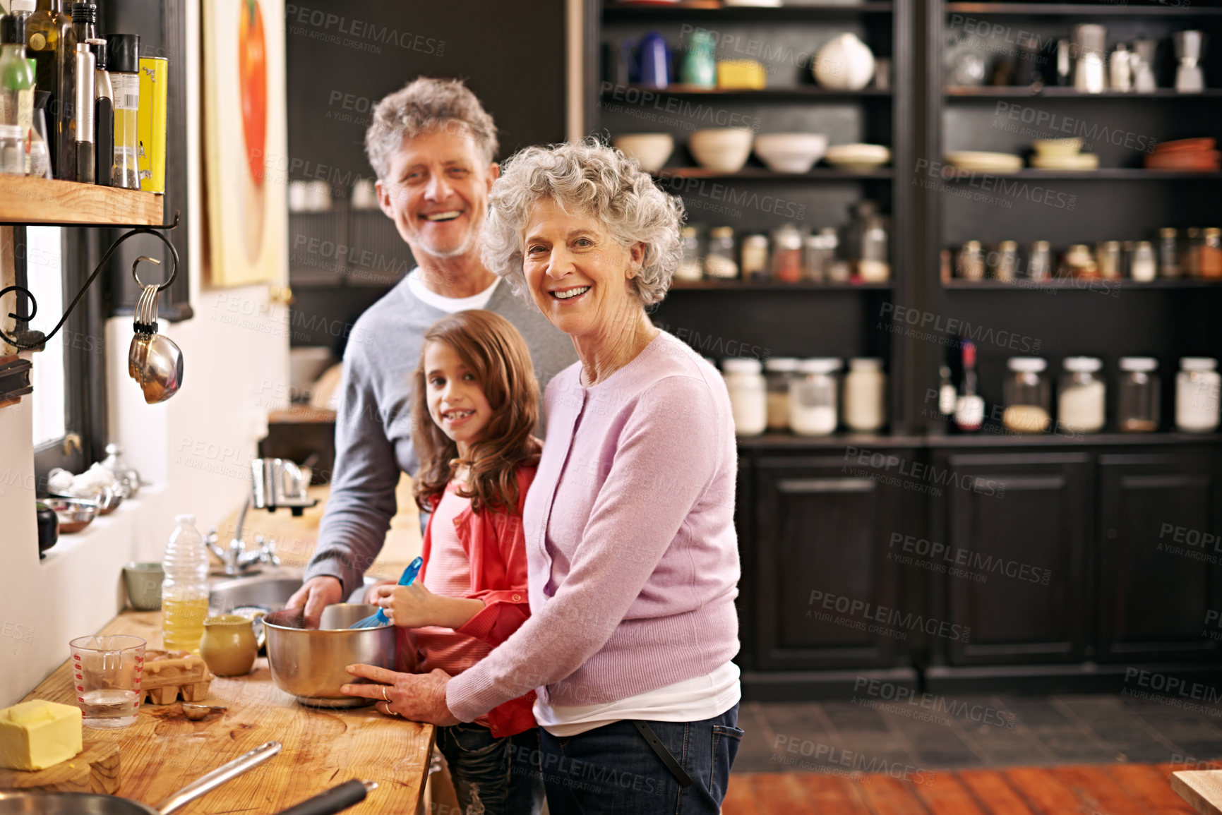 Buy stock photo Portrait of a little girl and her grandparents baking together in the kitchen