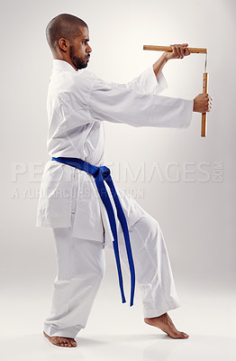 Buy stock photo Karate, fight and man with nunchaku in martial arts, studio or training with weapon for defence on white background. Nunchucks, exercise and fighting with equipment in sport with skill and power