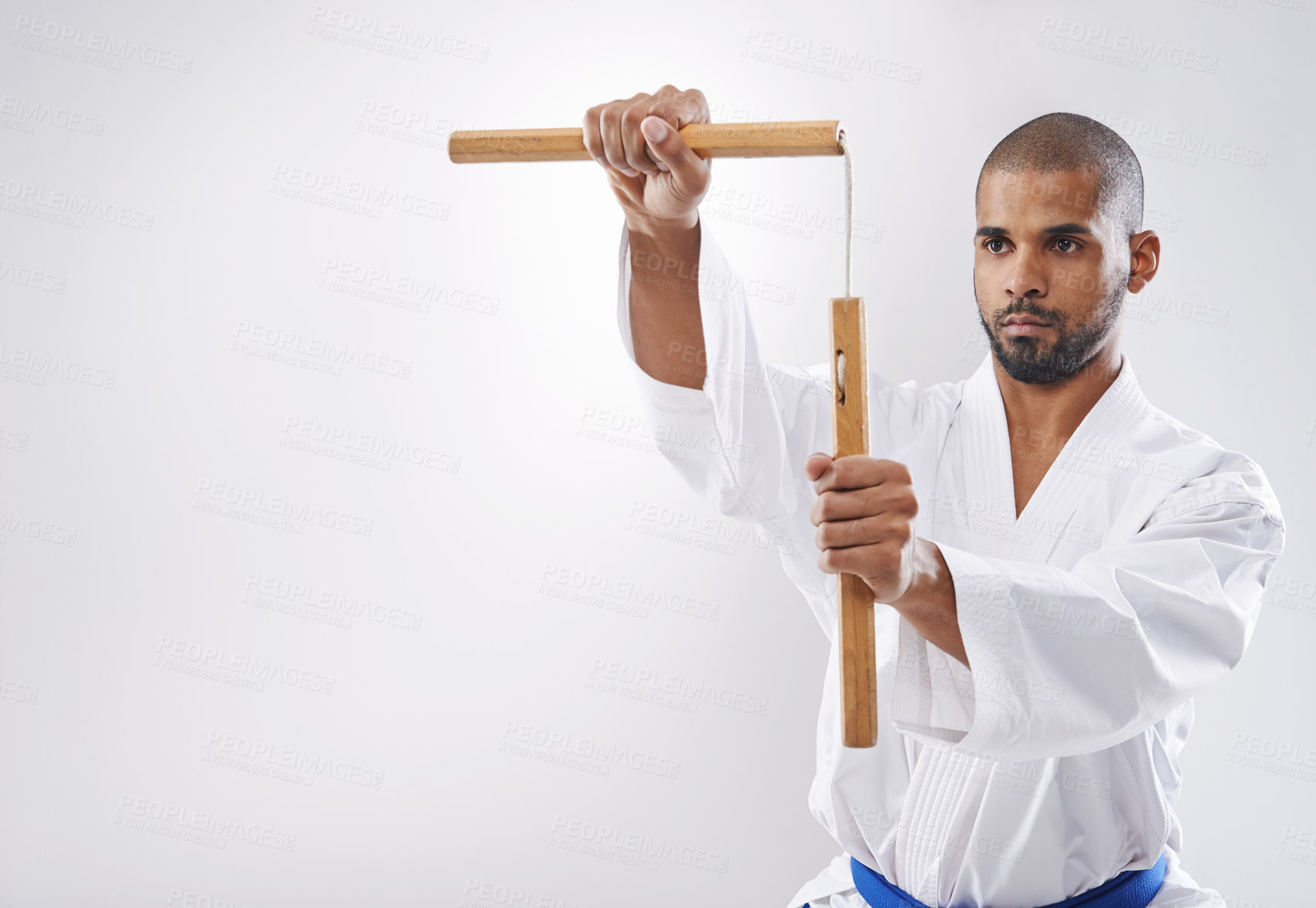 Buy stock photo Nunchucks, karate and man in martial arts fight with weapon in training for defence in white background of studio. Nunchaku, exercise and fighting with equipment in sport with skill and power in club