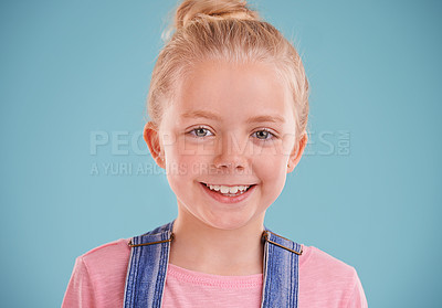 Buy stock photo Portrait, girl and kid with smile, happiness and cheerful child on a blue studio background. Face, mockup space or model with expression or excited with emotion or joyful with fun or funny with peace