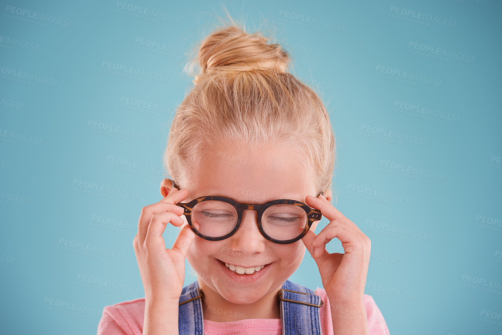 Buy stock photo Child, glasses and optometry vision in studio or healthy eyes on blue background for prescription, lenses or mockup space. Female person, smile and frame spectacles or development, growth or wellness