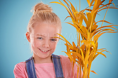 Buy stock photo Girl, studio and plant with smile, portrait and fun for childhood growth and fun. Child, youth and happiness with yellow, pastel and vibrant joy for cute kid isolated on colorful blue background