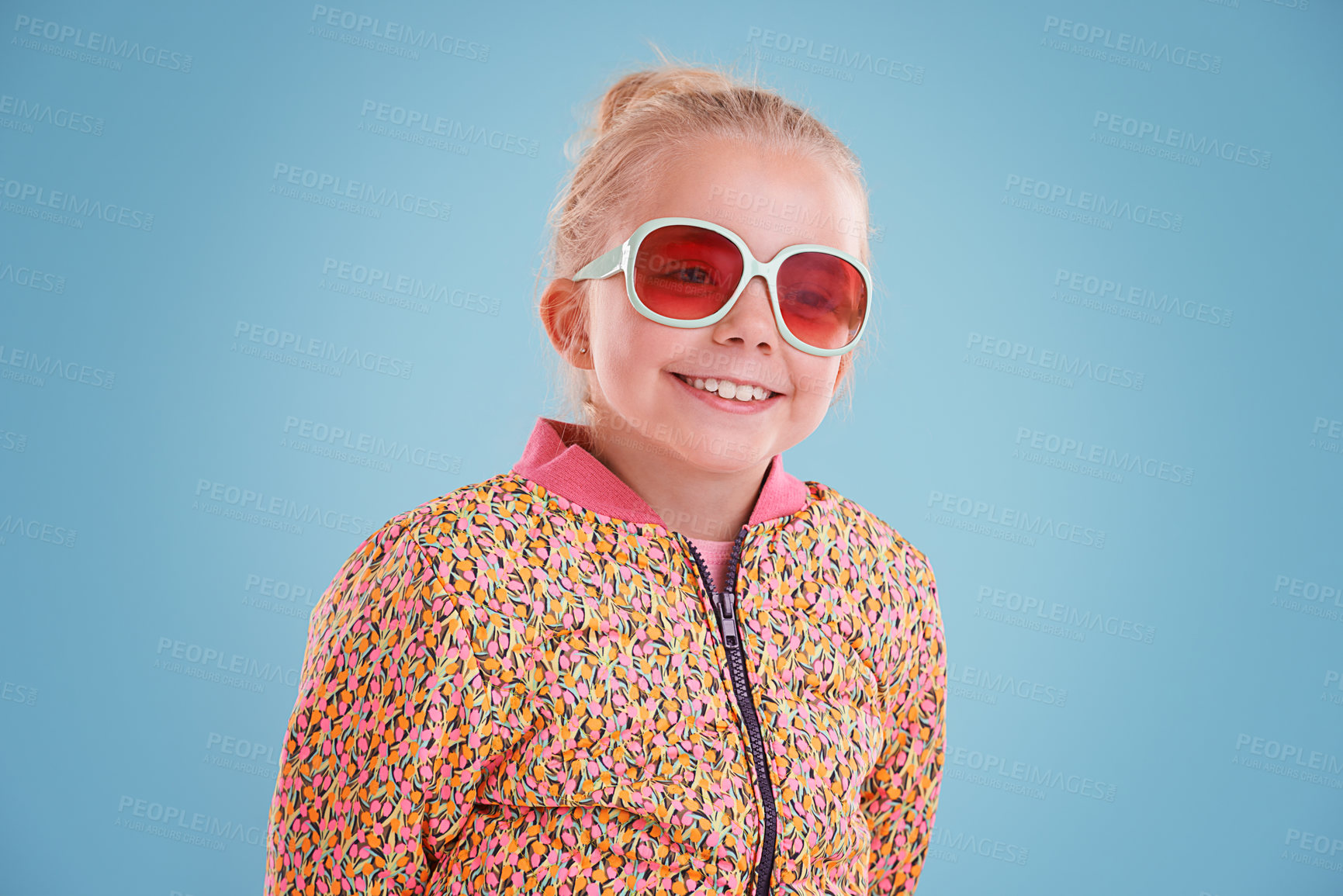 Buy stock photo Happy, sunglasses and girl child in studio with funky, trendy and stylish jacket for outfit. Excited, smile and face of young kid model with cool fashion and accessory isolated by blue background.