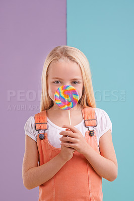 Buy stock photo Studio, girl and hiding with lollipop, dessert and playful for snack and childhood. Child, sweets and yummy candy for tasty, eating and happiness on vibrant split pastel pink and blue background