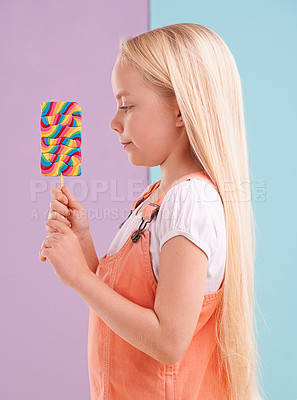 Buy stock photo Studio, girl and decision with lollipop, dessert and choice for snack and childhood. Child, sweets and yummy selection for tasty, eating and choosing on vibrant split pastel pink and blue background