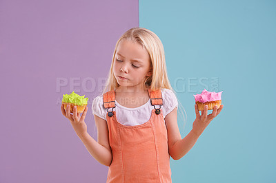 Buy stock photo Studio, girl and choice with cupcakes, dessert and decision for snack and childhood. Child, sweets and yummy selection for tasty, eating and choosing on vibrant split pastel pink and blue background