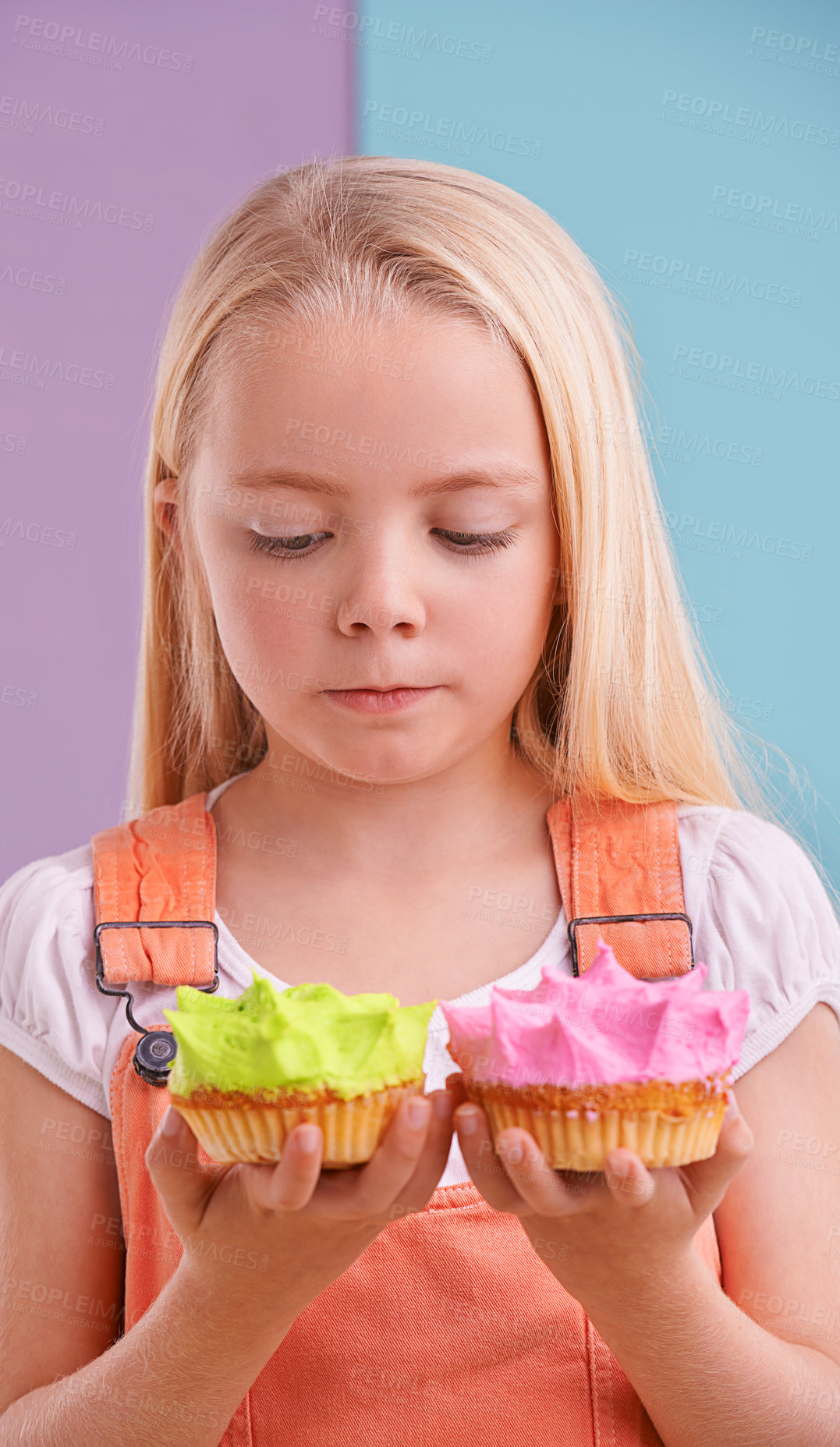 Buy stock photo Studio, girl and decision with cupcakes, desert and choice for snack and childhood. Child, sweets and yummy selection for tasty, eating and choosing on vibrant split pastel pink and blue background