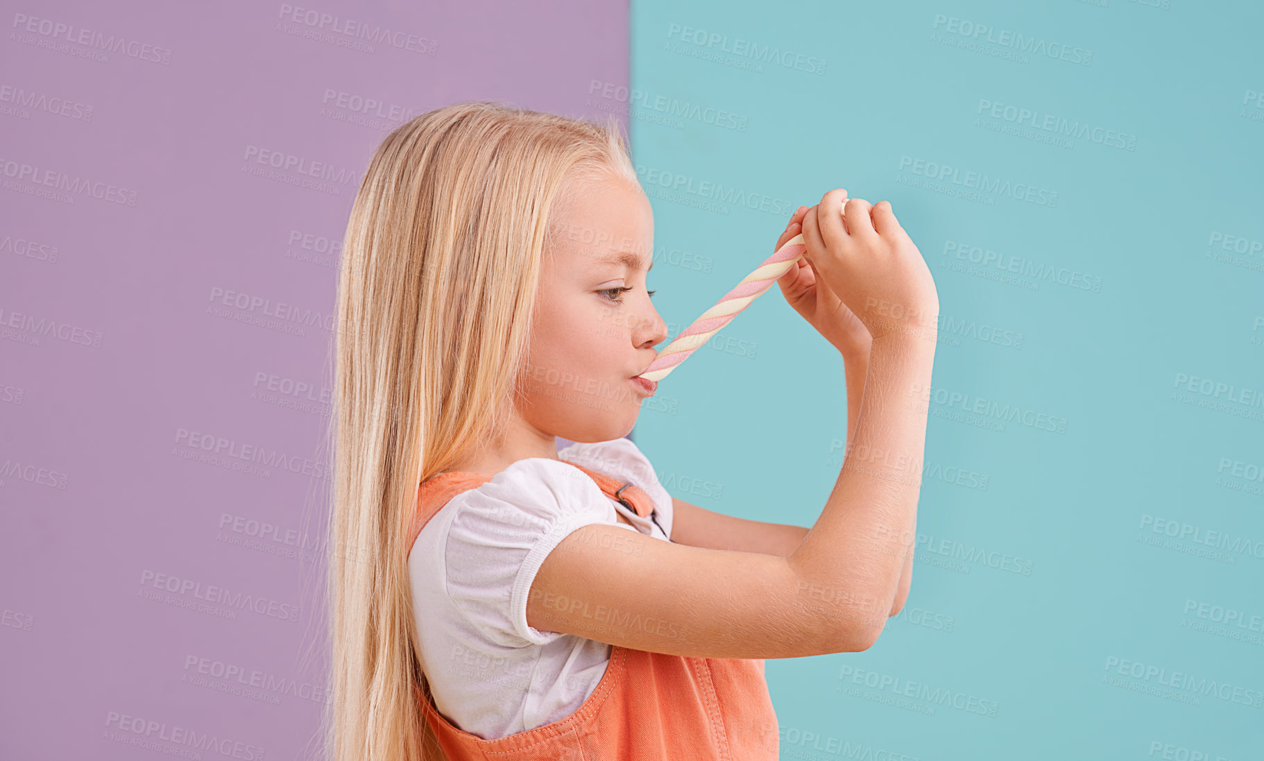 Buy stock photo Child, candy and eating dessert in studio for unhealthy snack or sugar meal, sweets or mockup space. Female person, food and split purple with blue background for party or lollipop, treat or hungry