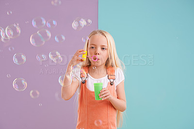 Buy stock photo Child, blowing bubbles and playing in studio as holiday activity for leisure, childhood development or mockup space. Female person, kid and toy or split purple with blue background, innocent or fun