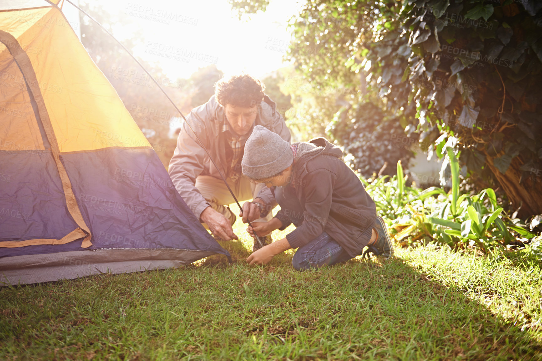 Buy stock photo Father, child and preparing tent for camping outdoor in nature on vacation while bonding in summer sunset. Dad, boy and setting up camp, learning and getting campsite ready in forest for travel.