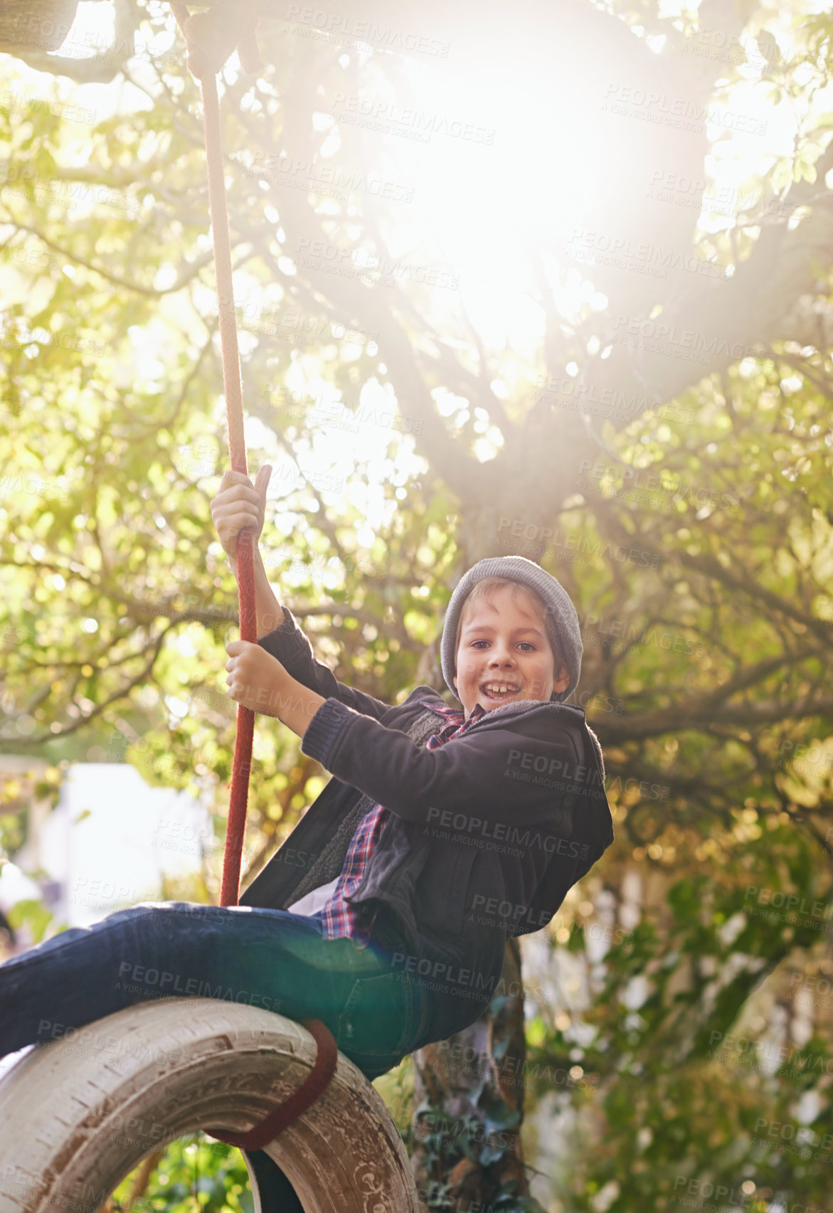 Buy stock photo Boy, tyre swing and portrait outdoor with happiness, playing and countryside vacation in summer. Child, face and diy adventure playground in garden of home with sunlight, trees and excited in nature