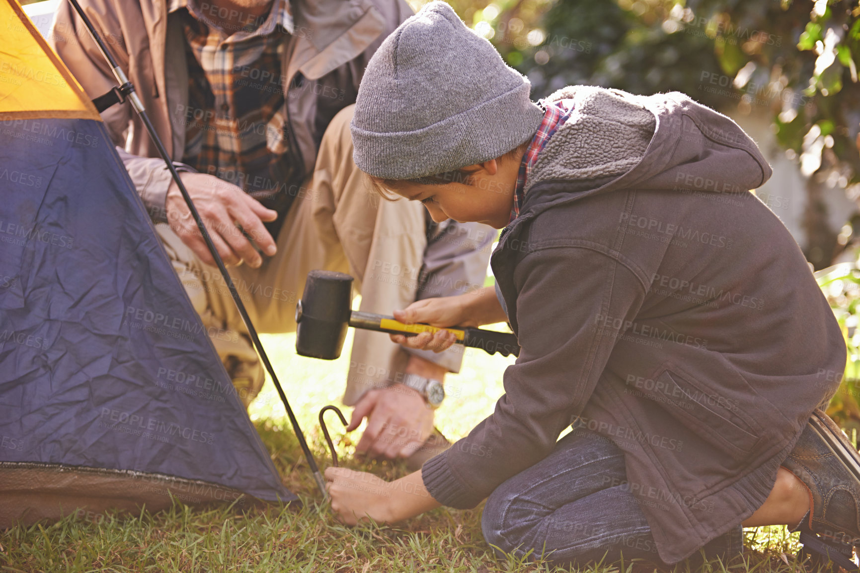 Buy stock photo Dad, kid and hammer tent for camping outdoor in nature on vacation, bonding together and summer. Father, boy and preparing camp, learning and helping in forest for travel, education and adventure.