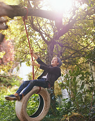 Buy stock photo Boy, child and playing on tyre swing in garden with happiness, recreation or countryside vacation in summer. Kid, excited and diy adventure playground in backyard with sunlight and trees in nature