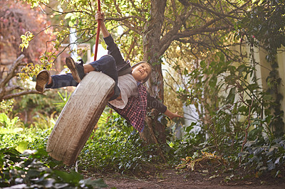 Buy stock photo A preteen boy swinging on a tyre swing in the garden