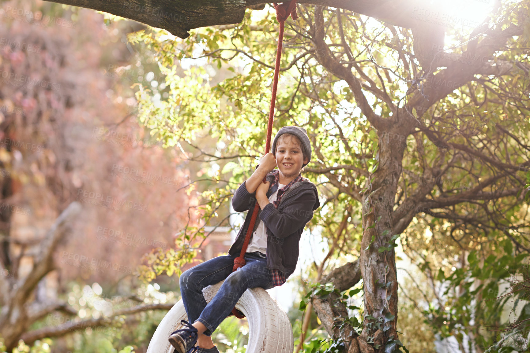 Buy stock photo Boy, tyre swing and portrait in garden with happiness, playing and countryside vacation in summer. Child, face and diy adventure playground in backyard of home with sunlight, trees or smile in nature