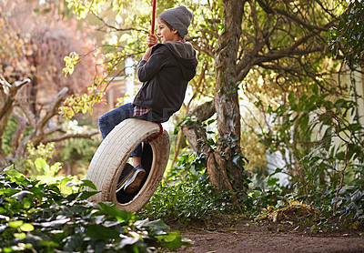 Buy stock photo Boy, tyre swing and playing in garden with happiness, recreation and countryside vacation in summer. Child, smile and diy adventure playground in backyard of home with sunshine and trees in nature