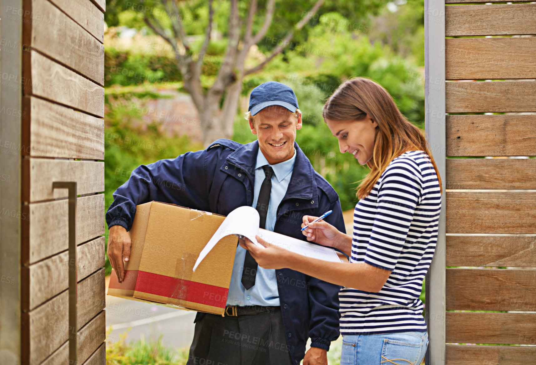 Buy stock photo Shot of a male courier delivering a package to a woman at her home