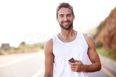 Buy stock photo Portrait of a handsome young man standing outdoors with an MP3 player