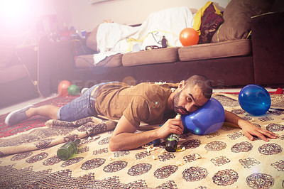 Buy stock photo Drunk, party and man hangover on a balloon pillow with a beet bottle after a home social event. Alcohol, fun weekend and hungover alcoholic person after a drink addiction or problem feeling tired 