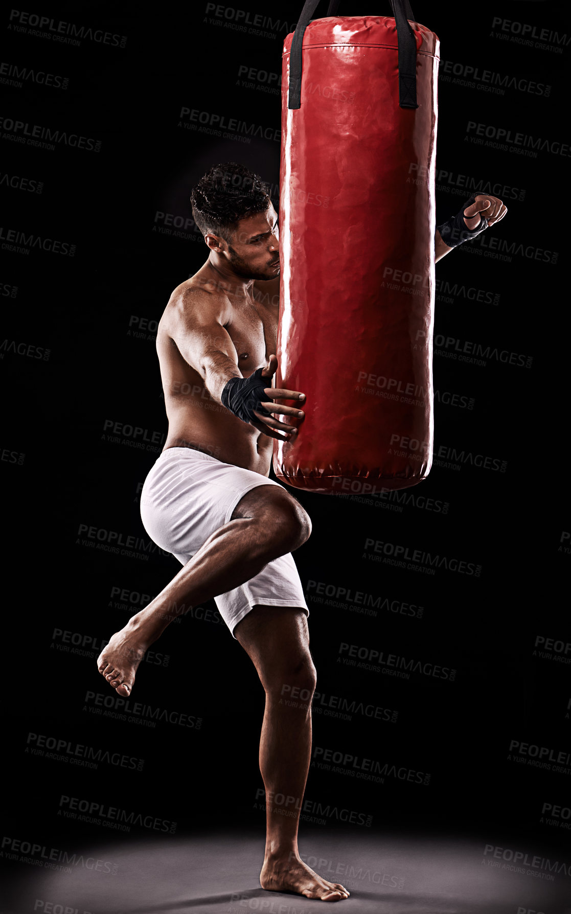 Buy stock photo Fitness, kick and punching bag by man boxer in studio for body, training or performance on black background. Impact, knee and topless athlete with martial arts, mama or kickboxing match practice