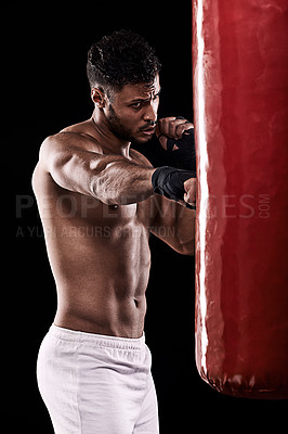 Buy stock photo Studio shot of kick boxer working out with a punching bag against a black background