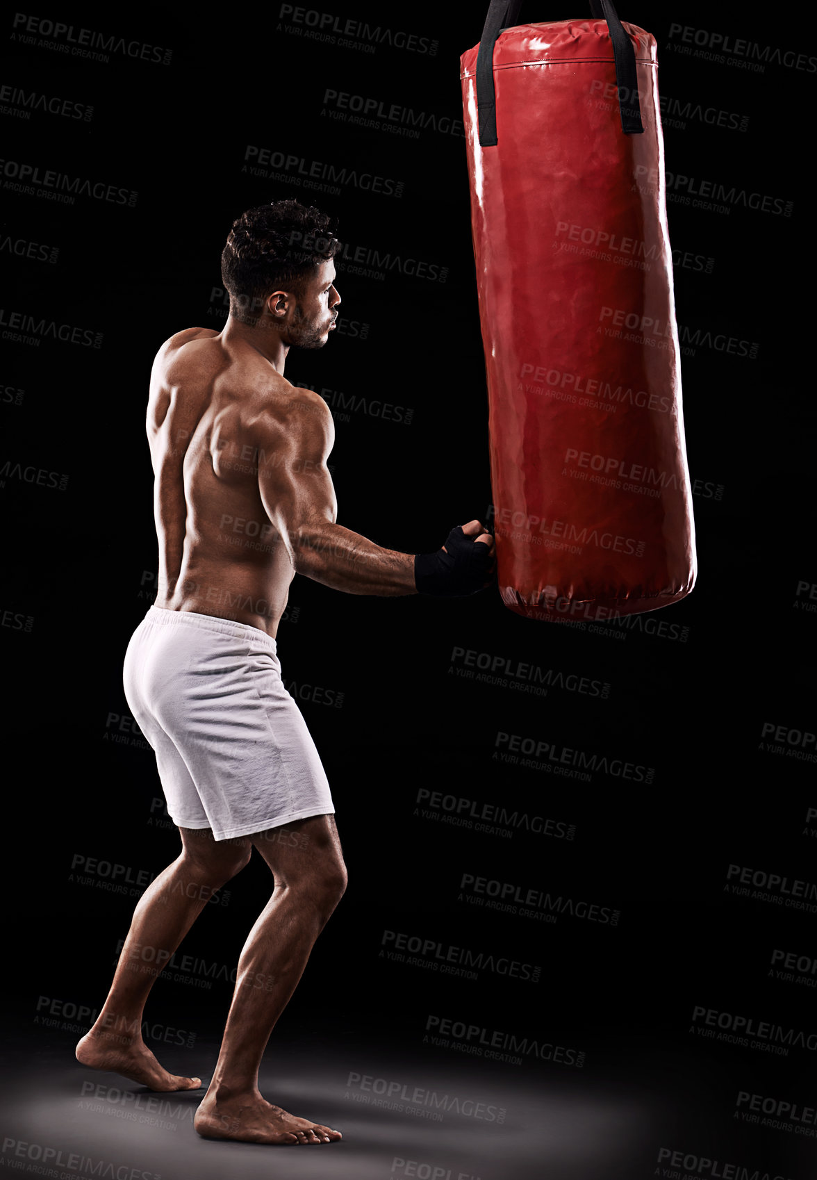 Buy stock photo Practice, boxer and man with punching bag in studio with gloves for training with strength and muscle. Adult, athlete and male person in dark background, healthy and power with body, job and sport