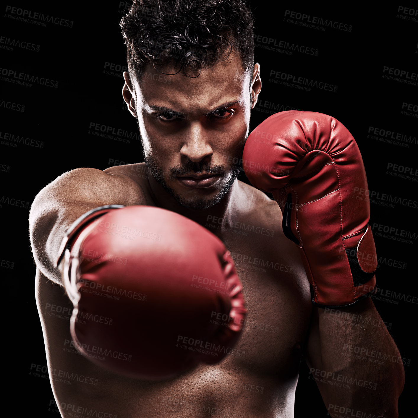 Buy stock photo Portrait of a young man wearing boxing gloves against a black background