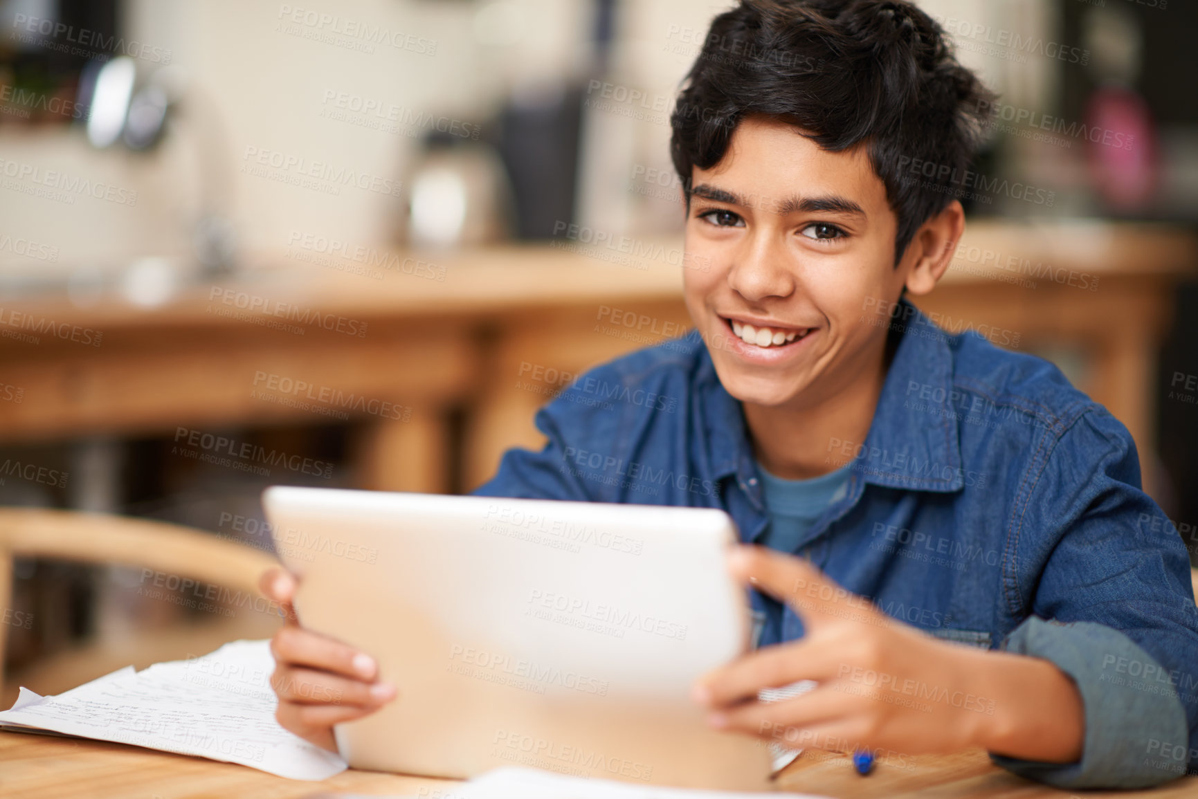 Buy stock photo Portrait of a young teenage boy using a digital tablet while doing his homework