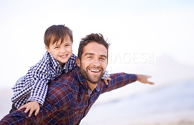 Buy stock photo A father carrying his young son on his back with a smile