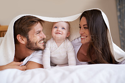 Buy stock photo Happy family, parents and baby with blanket on bed for love, care and quality time together. Mother, father and playful newborn child relaxing in bedroom with bedding fort, smile and bonding at home