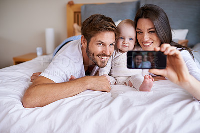 Buy stock photo Mother, father and smile for selfie with baby on bed in home for love, care or social media together. Happy family, parents and cute kid taking photograph for memory, happiness and relax in bedroom