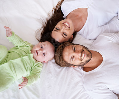 Buy stock photo Top view portrait of mother, father and baby on bed for love, care and quality time together at home. Happy parents, family and cute newborn kid relax in bedroom with smile, support and fun bonding