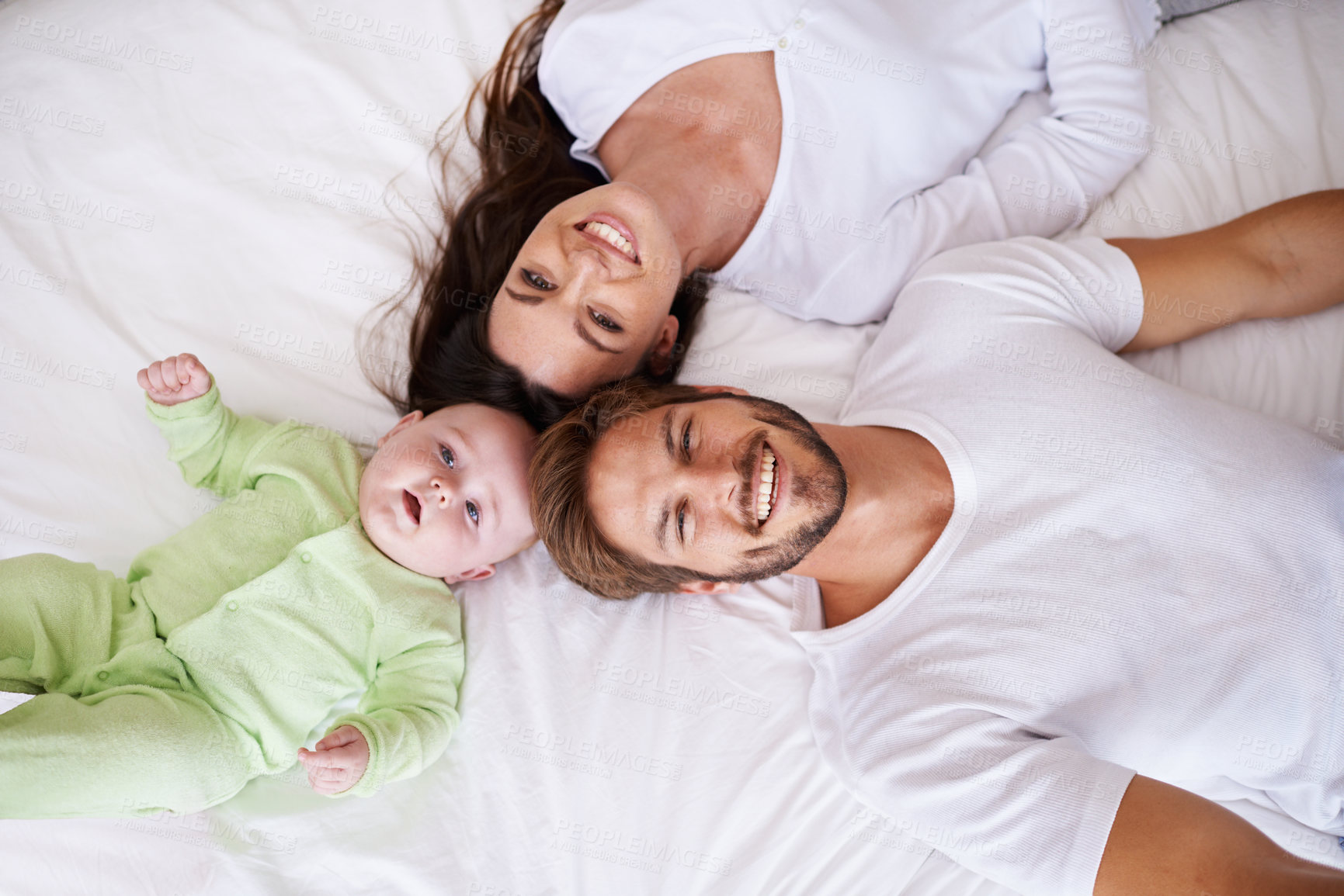 Buy stock photo Top view of portrait, mother and father with baby on bed for love, care and quality time together. Happy parents, family and newborn child relaxing in bedroom for smile, happiness and bonding at home