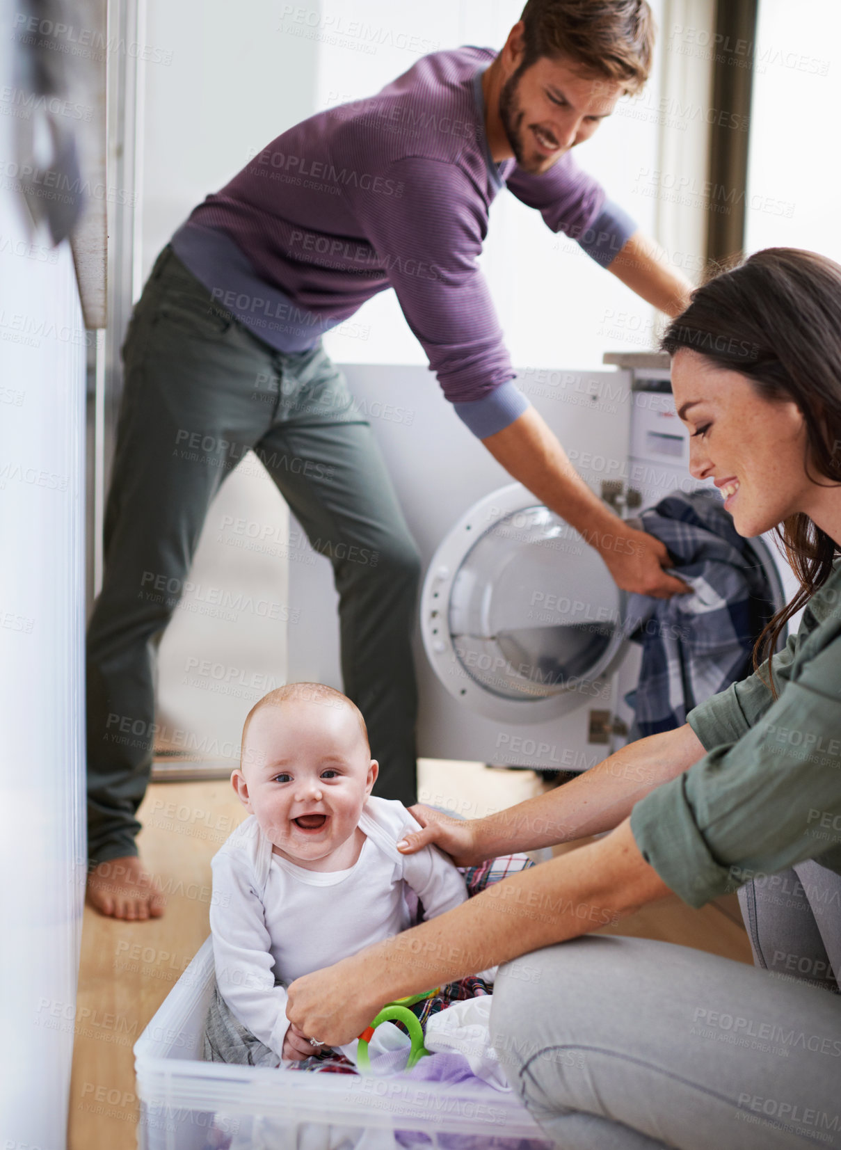 Buy stock photo Shot of a young family having fun while doing laundry