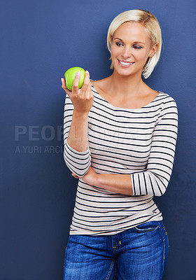 Buy stock photo Woman, smile and apple in studio for healthy diet on blue background or fruit nutrition, snack or fibre. Female person, relax and wellness eating with mockup space or vegan detox, food or lose weight