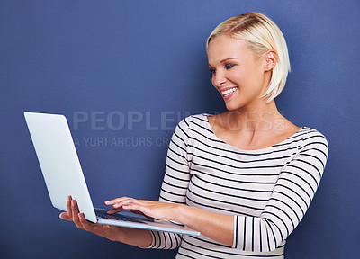 Buy stock photo Woman, smile and laptop in studio for research, internet and online for relax and website for break indoor. Young person or freelancer and happy with tech for typing, email and connection on mockup  