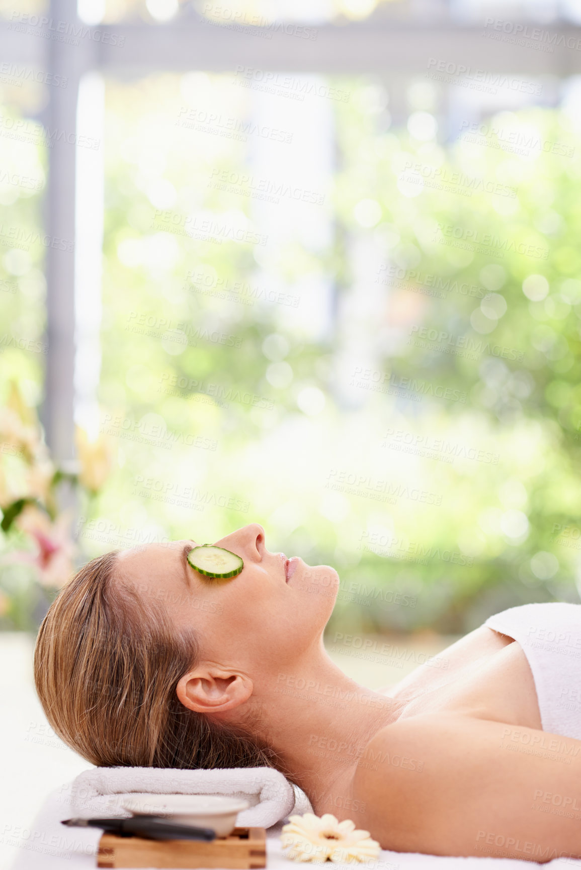 Buy stock photo Woman, relax and sleeping with cucumber on towel at spa for facial treatment, care or peace at hotel or resort. Calm young female person in relaxation, zen or stress relief for beauty or skincare