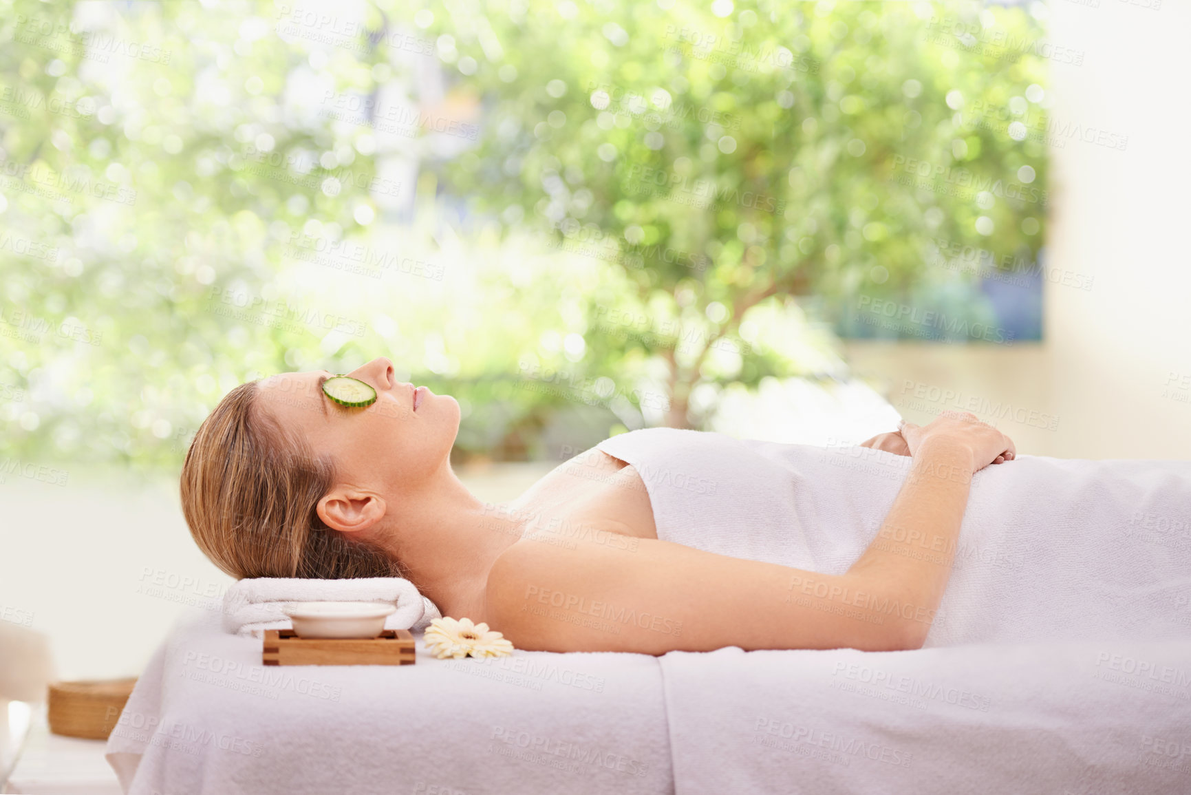 Buy stock photo Woman, massage and spa with cucumber facial for skincare treatment or wellness, detox or stress relief. Female person, eyes closed and calm on table at zen resort for luxury, peace or comfortable