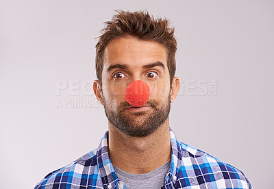 Buy stock photo Studio shot of a handsome man wearing a red nose against a gray background